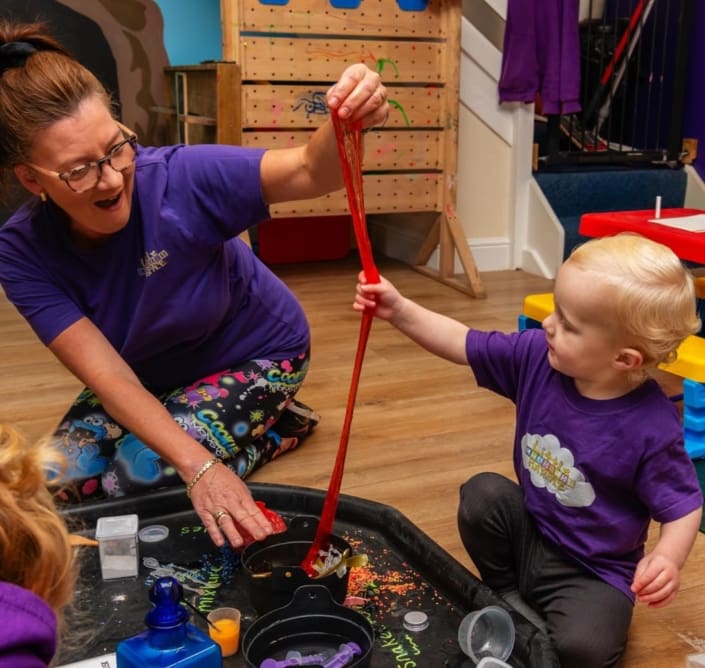 A lady wearing a little learners uniform plays with a child